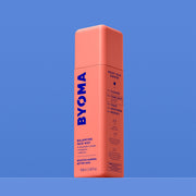 Une bouteille BYOMA Balancing Face Mist, vue en angle montrant les étapes de routine « Boost Your Barrier » sur le panneau latéral, sur fond bleu.