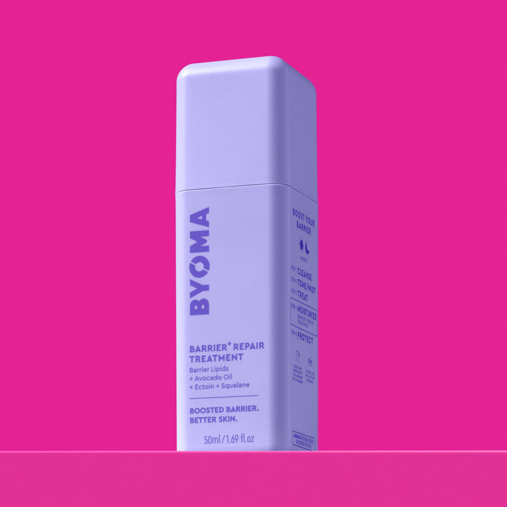 Une bouteille de traitement réparateur BYOMA Barrier+, vue en angle montrant les étapes de routine « Boost Your Barrier » sur le panneau latéral, sur fond rose.