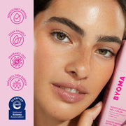 Femme tenant un produit de soin Byoma avec des icônes de marque sur fond rose
