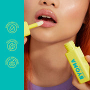 Personne appliquant un baume à lèvres jaune sur ses lèvres avec la marque du produit visible.