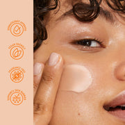 Gros plan d'une personne appliquant de la crème sur son visage avec un fond beige et des icônes indiquant les caractéristiques du produit.