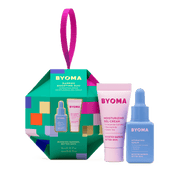 Un coffret cadeau vert multicolore en forme d'ornement intitulé « BYOMA Barrier Boosting Duo », comprenant un tube rose de gel-crème hydratant et une bouteille bleue de sérum hydratant.   Le fond est transparent.